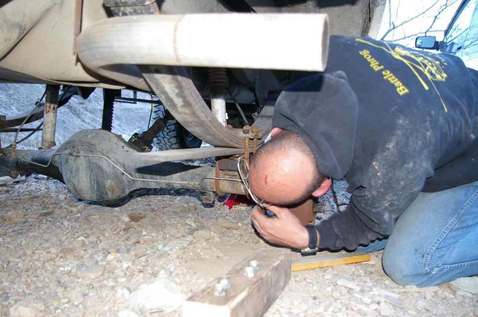 Man inspecting rear axle and exhaust system of a vehicle