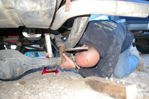 1986 Ford Bronco - Mechanic works on the rear suspension and axle assembly of an off-road vehicle.
