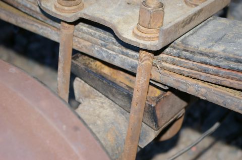 1986 Ford Bronco - Close-up view of a rusty leaf spring assembly, showing U-bolts and fasteners.