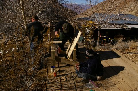 1986 Ford Bronco - People work on a wooden structure outdoors near a weathered building.
