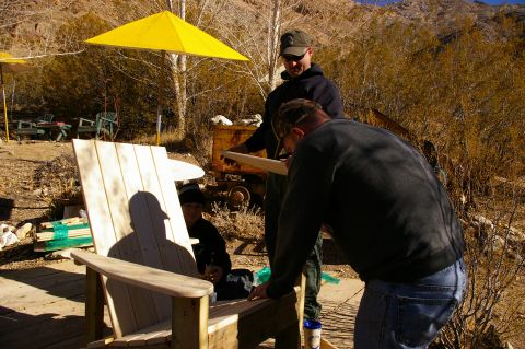 1986 Ford Bronco - Three people work on building a wooden chair outdoors with mountains in the background.