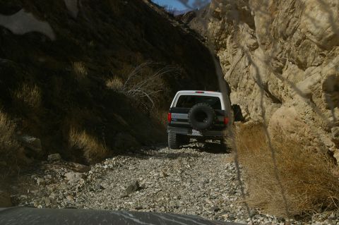 1986 Ford Bronco - A Ford Bronco navigates a tight, rocky path through a canyon.