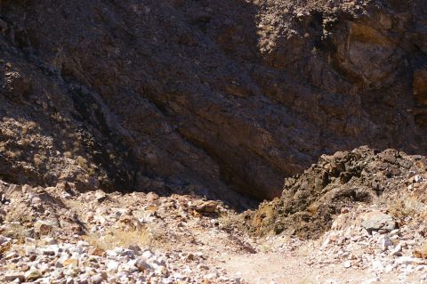 1986 Ford Bronco - A desert scene with rough, rocky ground and large rock faces under a bright sky.