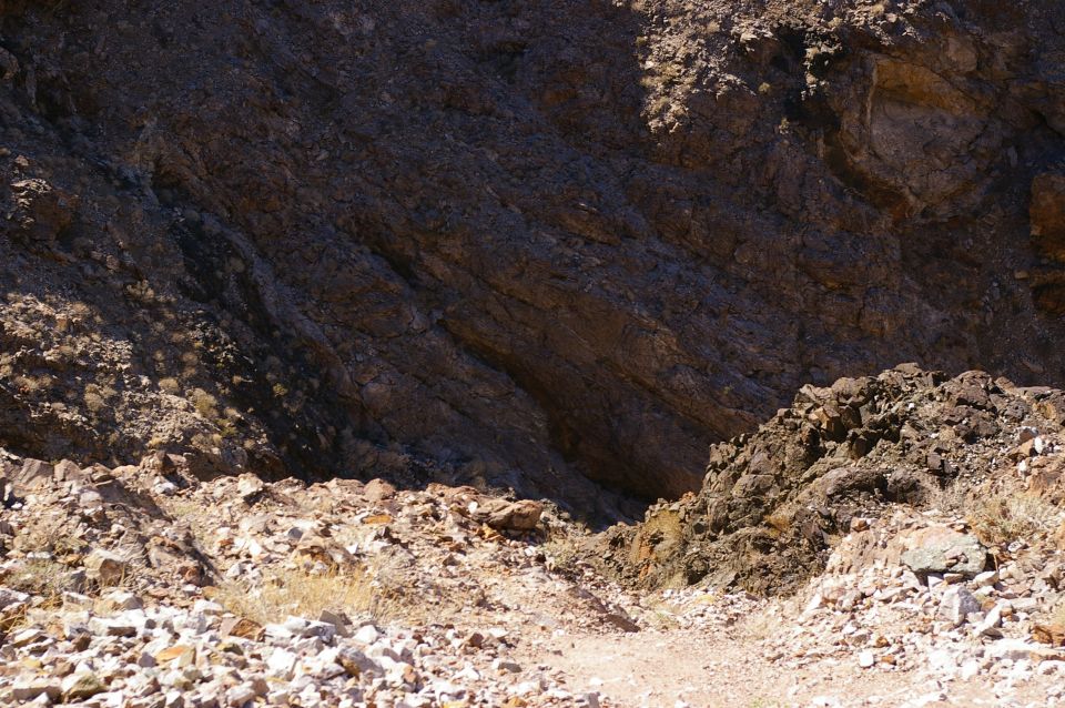 Rocky terrain with a path leading into a shadowed area between rock formations