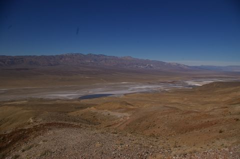 1986 Ford Bronco - A vast desert landscape stretches out under a clear blue sky, mountains and a dry lake bed.