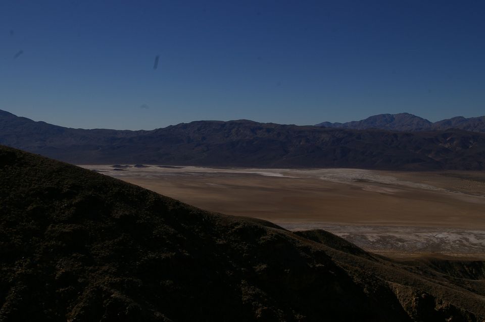 Desert valley with dry lake bed and mountains under a clear blue sky
