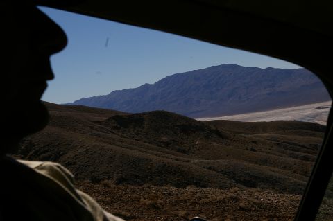 1986 Ford Bronco - A person's profile is silhouetted against a vast desert landscape seen through a car window.