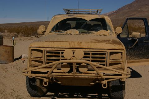 1986 Ford Bronco - This dusty off-road vehicle, possibly from the early 1980s, is seen from the front in a desert environment, with another vehicle partially…