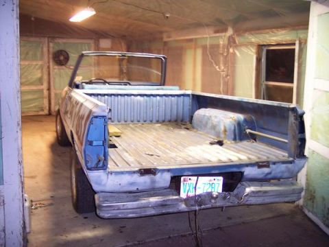 1981 Dodge Power Ram - Rear view of a 1981 Dodge Power Ram pickup truck, showing the bed and bumper. The truck appears to be in a garage.
