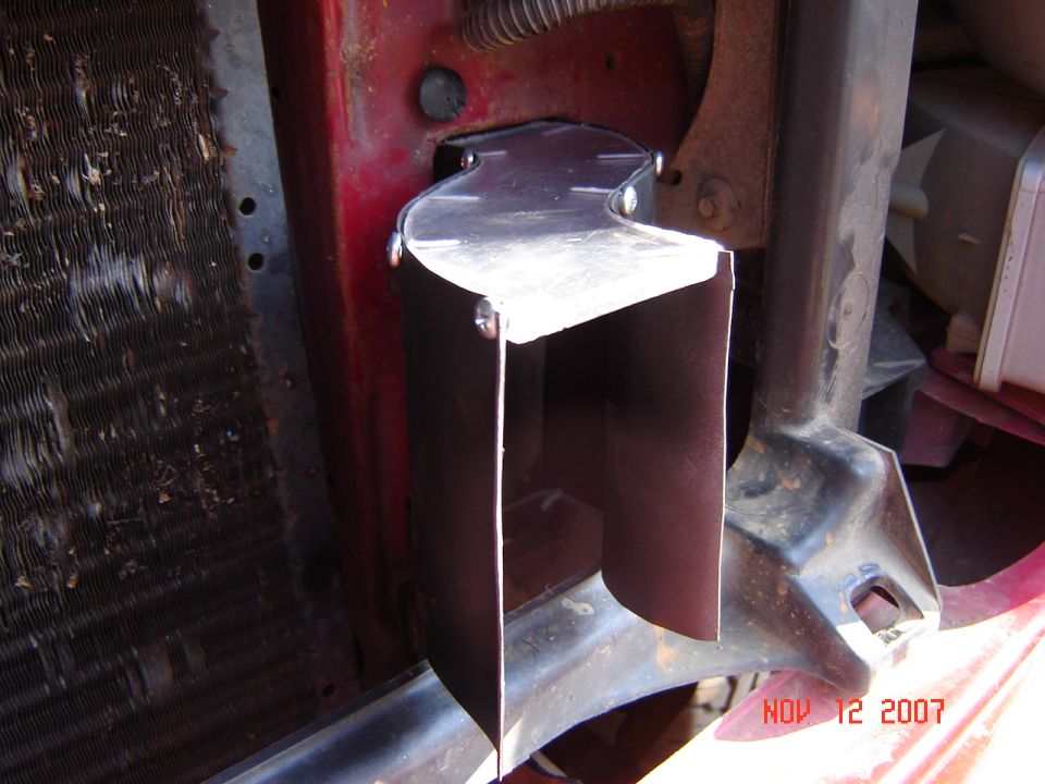 Sheet-metal bracket bolted to a red truck frame near the radiator