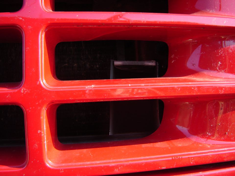 Close-up of a red plastic vehicle grille with rectangular slots