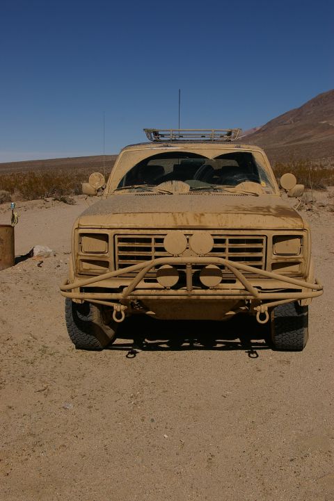 1986 Ford Bronco - Desert-camouflaged pickup truck with custom bumper and roof rack.