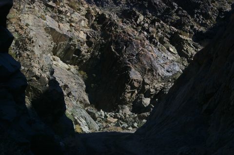1986 Ford Bronco - A dirt path winds through a canyon, illuminated by sunlight on the rock faces.