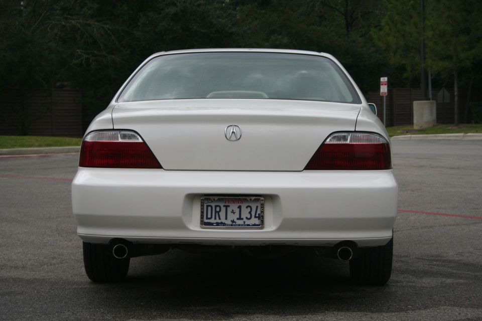 Rear view of white Acura TL sedan with Texas plate DRT 134 and dual chrome exhaust tips