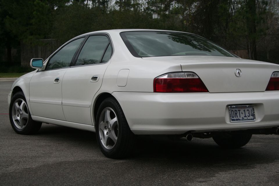 White Acura TL sedan rear 3/4 view with Texas plate DRT 134 and chrome exhaust tip