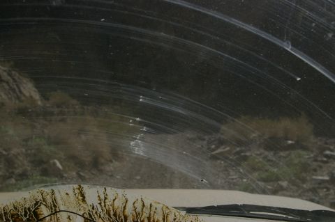 1986 Ford Bronco - Dirty windshield obscures the view of a desolate landscape with a rocky hillside.