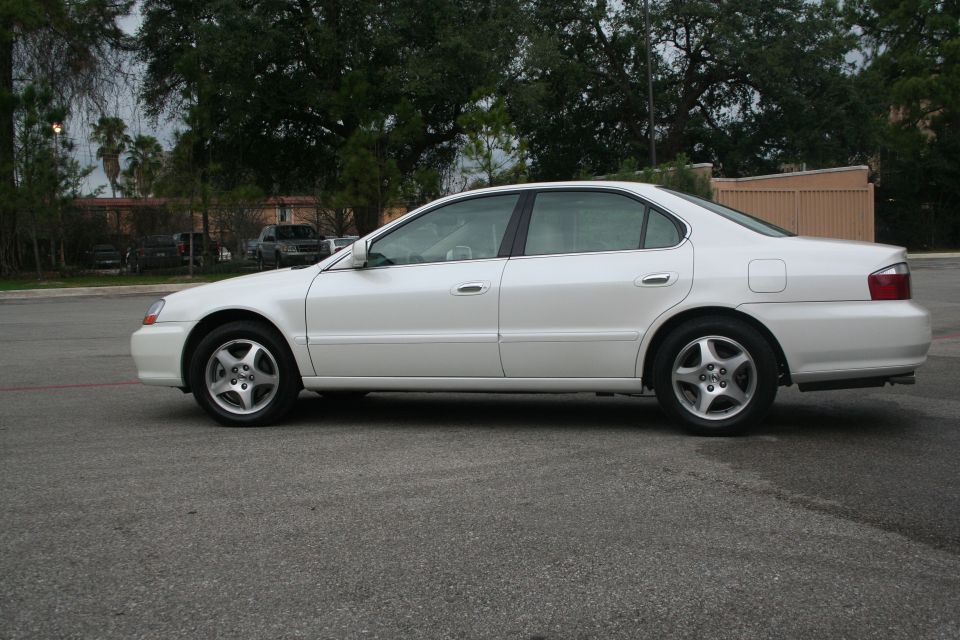 White Acura TL sedan side profile in empty parking lot