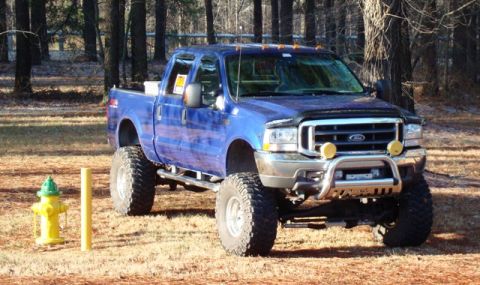 2003 Ford F-250 - This lifted 2003 Ford F-250 pickup truck is shown from a 3/4 front angle in an outdoor setting.
