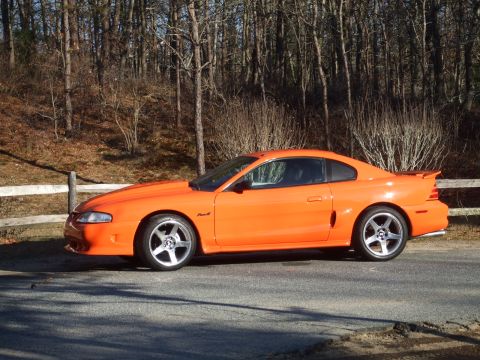 1995 Ford Mustang - Side view of an orange 1995 Ford Mustang coupe.