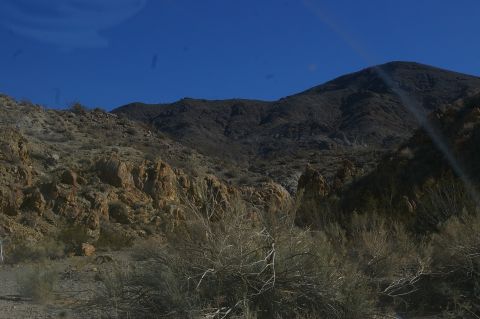 1986 Ford Bronco - A vast desert landscape with mountains and dry brush under a bright blue sky.