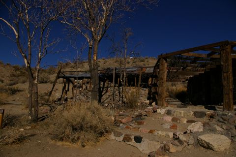 1986 Ford Bronco - A weathered stone structure with a partially collapsed wooden roof stands in a dry, arid environment.