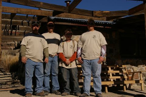 1986 Ford Bronco - A group poses for a photo in front of an unfinished wooden structure with a stone foundation.