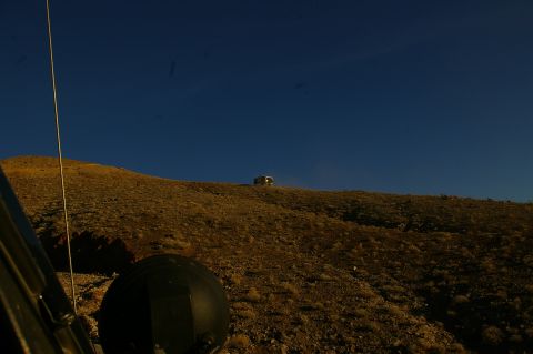 1986 Ford Bronco - A vehicle is parked on a hill under a clear blue sky, viewed from the perspective of another vehicle.