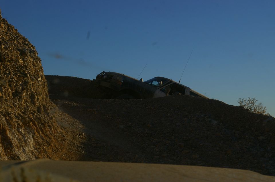 Off-road vehicle climbing a rocky hill under a clear blue sky