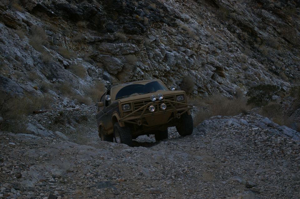 Tan off-road SUV driving on a rocky, desert trail