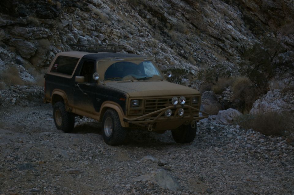 Brown and black Ford Bronco with off-road bumper and lights on rocky terrain