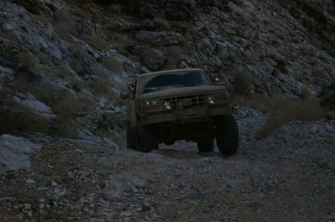 1986 Ford Bronco - Ford Bronco navigating a challenging off-road trail in a mountainous area.