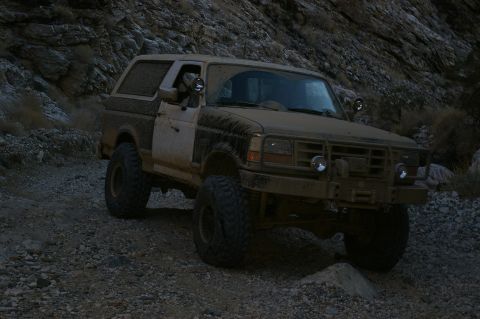 1986 Ford Bronco - This Bronco is navigating a rough, rocky trail in a mountainous area.