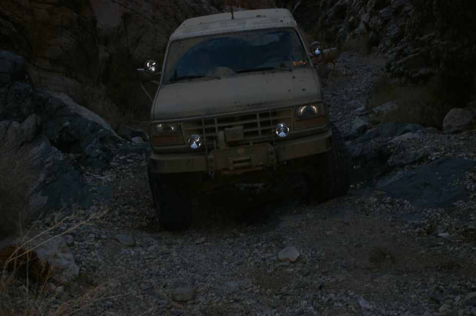 Tan Ford Bronco driving on a rocky, off-road trail in a canyon