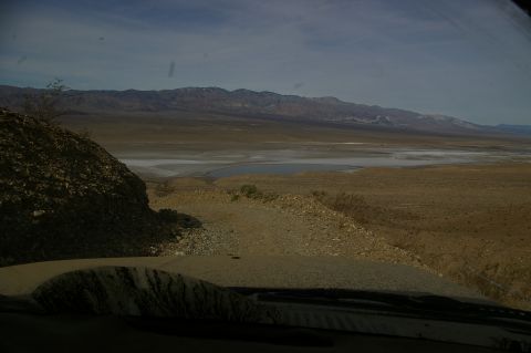 1986 Ford Bronco - The view from the dashboard shows a wide expanse of desert terrain under a partly cloudy sky.