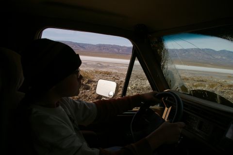 1986 Ford Bronco - View from inside a vehicle driving through a dry, desolate landscape with mountains in the distance.