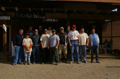 1986 Ford Bronco - A group of men gathered outside 'The Out Post' building, which has a welcome sign.