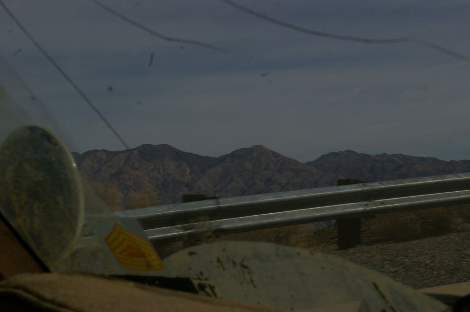 Interior view from a vehicle looking out at mountains and a guardrail