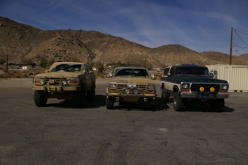 Three SUVs parked in a desert landscape. The one on the right is a 1978 Ford Bronco