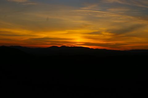 1986 Ford Bronco - The sun sets behind a mountain range, casting vibrant colors across the sky.