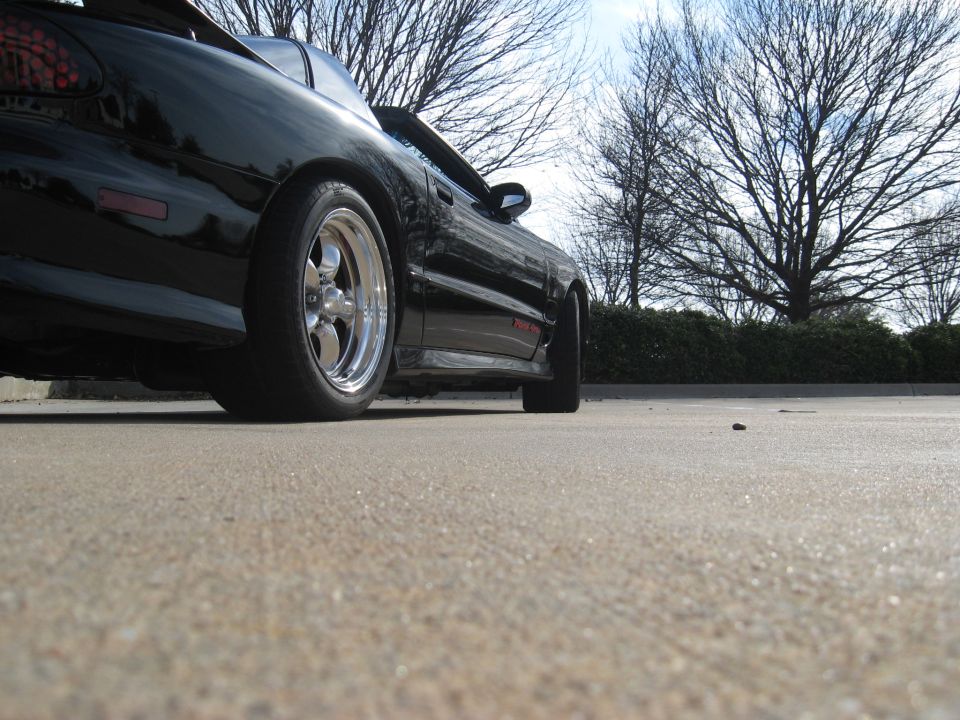 Black 2002 Pontiac Trans Am with chrome wheels, rear quarter view