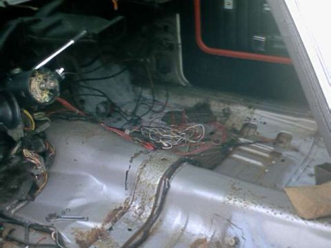 1976 Ford Ranchero - The interior of a vehicle shows significant disarray with exposed wiring and rust, indicating a state of disrepair.