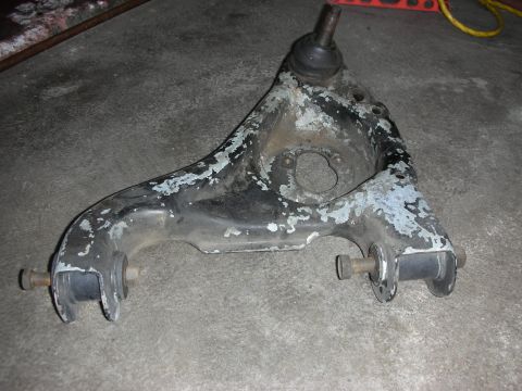 1998 Ford Crown Victoria - rear suspension control arm with twin bushings and a ball-joint stud, weathered paint, on concrete.