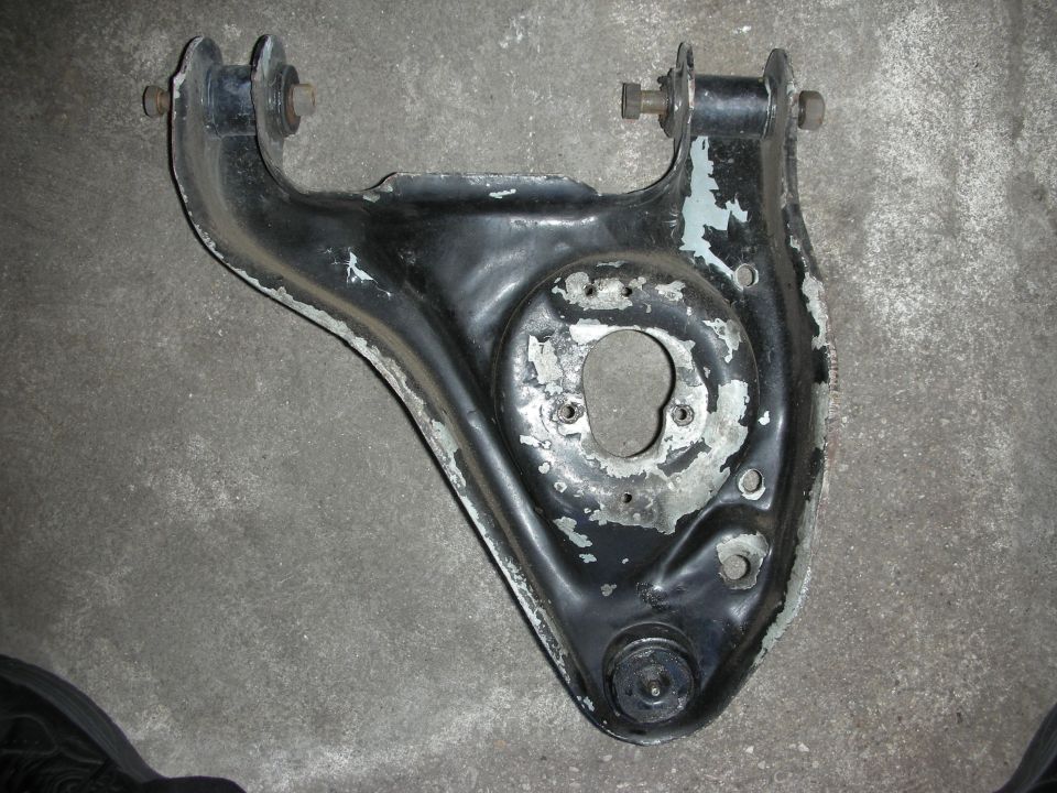 Black-painted suspension control arm with bushings on concrete floor