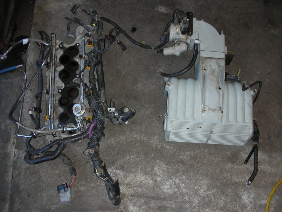 Disassembled engine wiring harness and intake manifold on garage floor