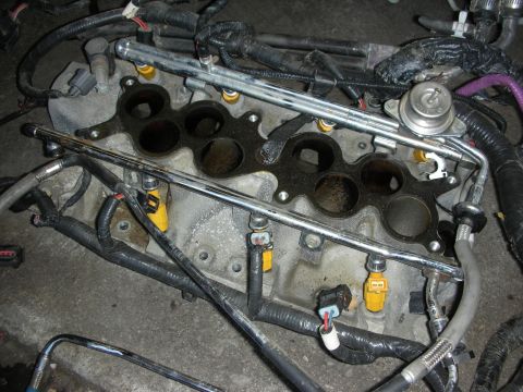 1998 Ford Crown Victoria - Close-up of an engine's intake ports and fuel rails with electrical injector connectors and wiring during disassembly.