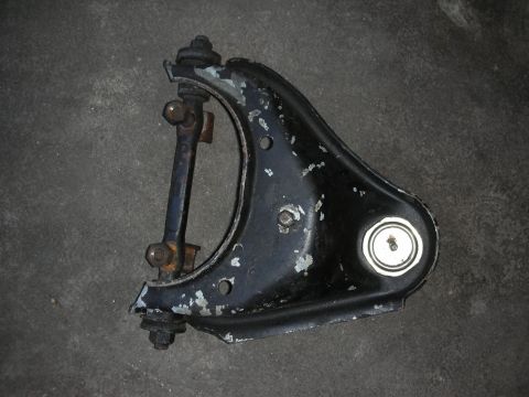 1998 Ford Crown Victoria - black-painted upper suspension control arm with a ball joint and pivot bushings, paint chipped, on a concrete floor.