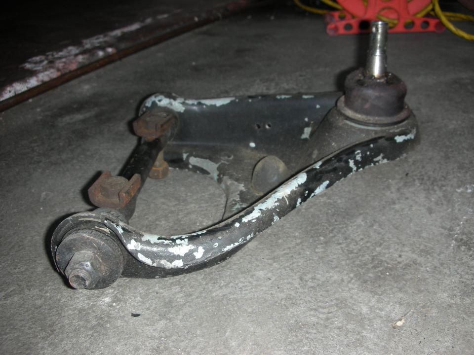Suspension control arm with ball joints resting on a garage floor