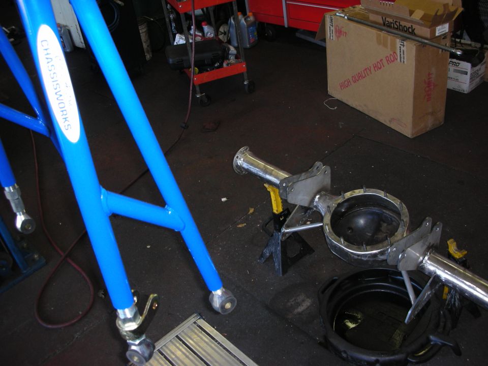 Blue tubular suspension arms and polished axle parts on shop floor