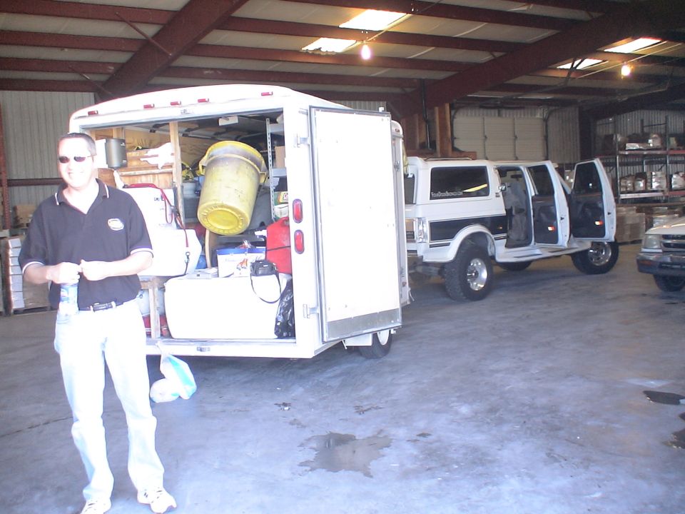 White van with black trim, open doors, and large tires parked inside a warehouse
