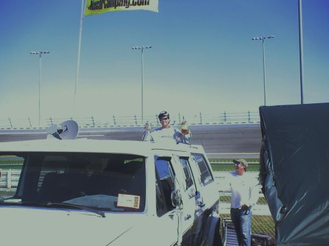 1993 Ford C-350 (Centurion Conversions) - Two men are at a race track, one standing on top of a van and holding drinks.